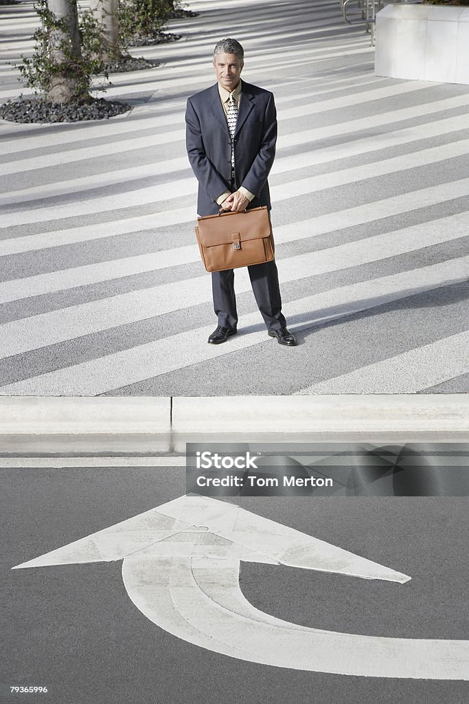Businessman outdoors by street with arrow pointing towards him  Blame Stock Photo