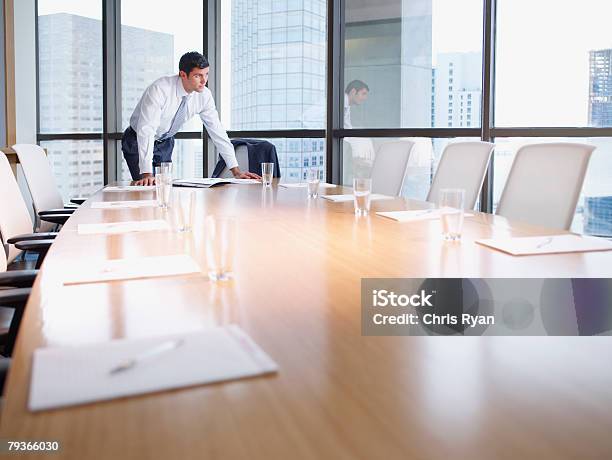 Photo libre de droit de Homme Daffaires Dans La Salle De Conseil Avec Documents Par De Grandes Fenêtres banque d'images et plus d'images libres de droit de Bureau - Lieu de travail