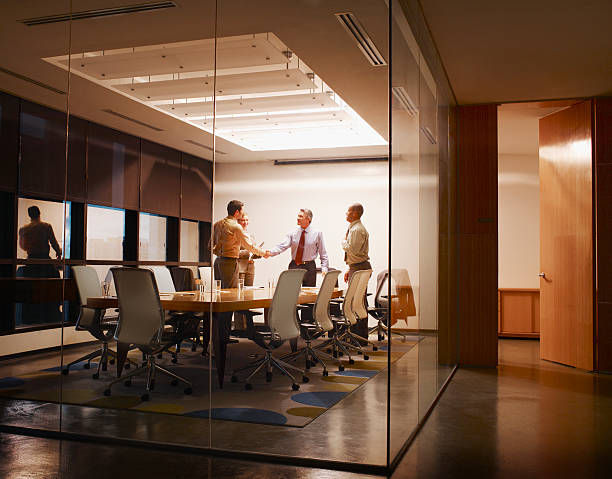 quatro empresários na sala de reuniões com dois dar um aperto de mão - board room business meeting office imagens e fotografias de stock