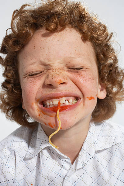 jeune garçon à l'intérieur de manger des spaghettis - child eating pasta spaghetti photos et images de collection