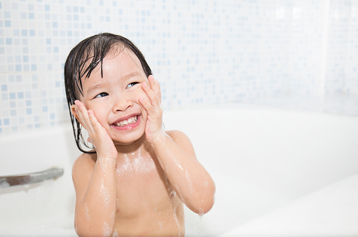 Happy funny baby laughing in the bath, look up with copy space