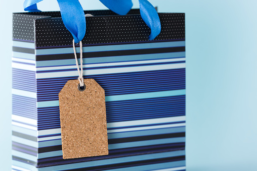 Close up of blank tag on blue striped paper bag