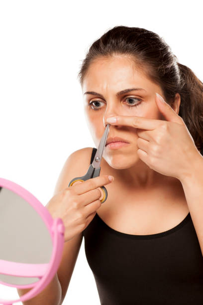 istock young woman removes hair from her nose using scissors 800178532
