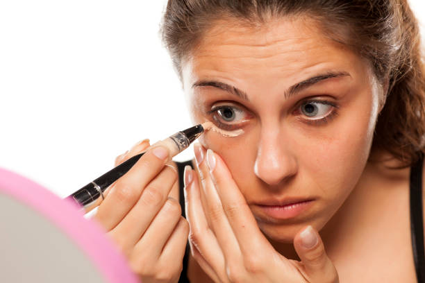 istock young beautiful woman apply concealer under the eyes 800179084