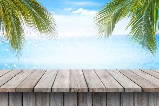 istock Empty wooden table and palm leaves on beach blurred background. 800240242
