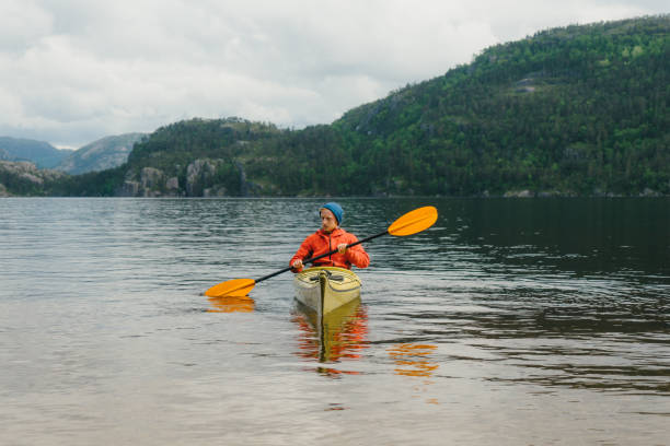 istock Man  in red coat kayaking on the lake in Norway 800248608