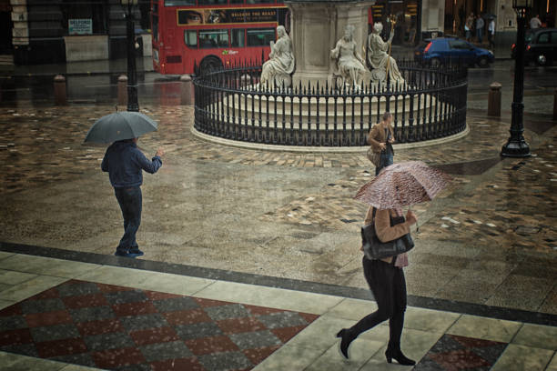 Paternoster Square, London Paternoster Square outside St Paul's Cathedral in London, UK with rain falling heavily and tourists with umbrellas walking across the place. paternoster square stock pictures, royalty-free photos & images