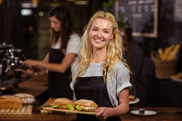 hübsche kellnerin hielt ein tablett mit brötchen - waitress stock-fotos und bilder