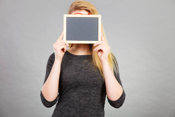 istock Woman holding blank black board on face 800303538