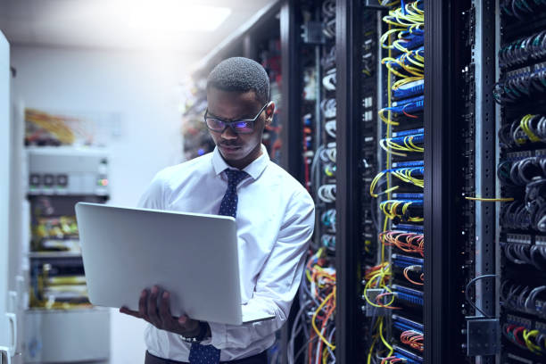 The man with the plan Cropped shot of a IT technician working on his laptop while standing inside of a server room hard drive photos stock pictures, royalty-free photos & images