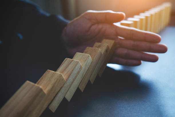 istock Problem Solving Close up view on hand of business woman stopping falling blocks on table for concept about taking responsibility. 800309622