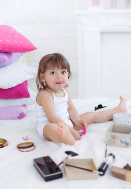 istock Little girl is playing while sitting on a white bed 800324756