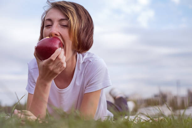 istock Very beautiful caucasian model eating red apple in the Park. 800327348
