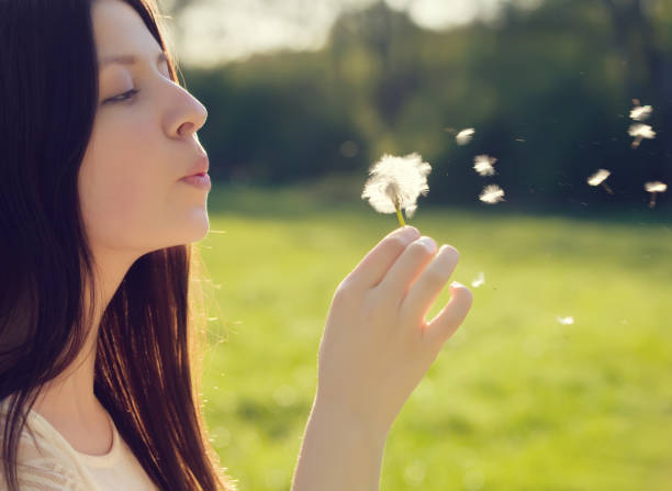 istock woman blowing on a dandelion 800331154