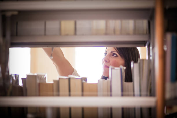 Blond student looking for book in library shelves at the university