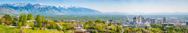 Salt Lake City downtown panorama overlooked by Wasatch Mountains Utah Blue skies and snow capped mountains above the landmarks of Salt Lake City, from the leafy suburbs and University campus to the monumental dome of the State Capitol and the ornamental spires of the Mormon Temple surrounded by the skyscrapers of downtown, Utah, USA. salt lake county stock pictures, royalty-free photos & images