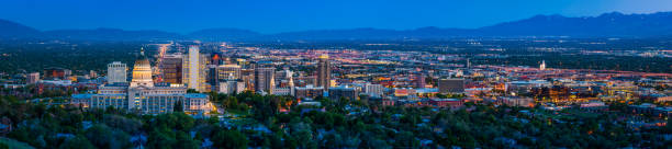 Salt Lake City downtown cityscape panorama illuminated at dusk Utah Blue dusk skies over the city lights and landmarks of Salt Lake City, the monument spotlit dome of the State Capitol and the ornamental spires of the Mormon Temple surrounded by the skyscrapers of downtown, Utah, USA. salt lake city mormon temple utah photos stock pictures, royalty-free photos & images