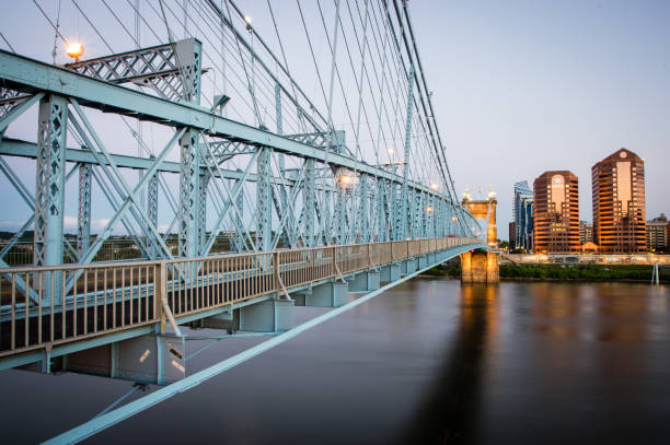 Steel structure of the John A. Roebling suspension bridge at dusk, stretching across the Ohio River.  It connects Cincinnati and Covington.  The structure was designed by John A. Roebling and constructed in 1866.  At the time of construction it was the world's longest suspension bridge.  Roebling went on to design the Brooklyn Suspension Bridge in New York City which was completed in 1883.