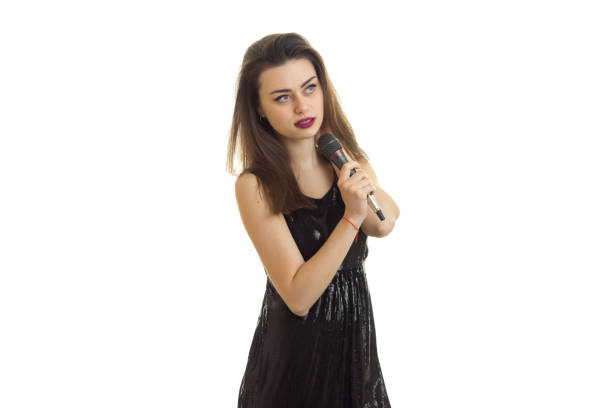istock woman in black dress with microphone in hands singing 800378476