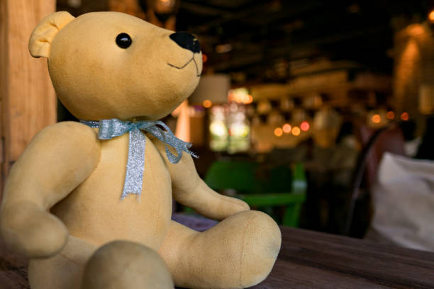 a little light brown cute bear sitting on the wooden table