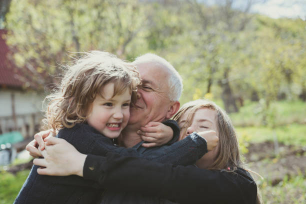 Grandfather and granddaughters in the back yard playing and hugging. stock photo