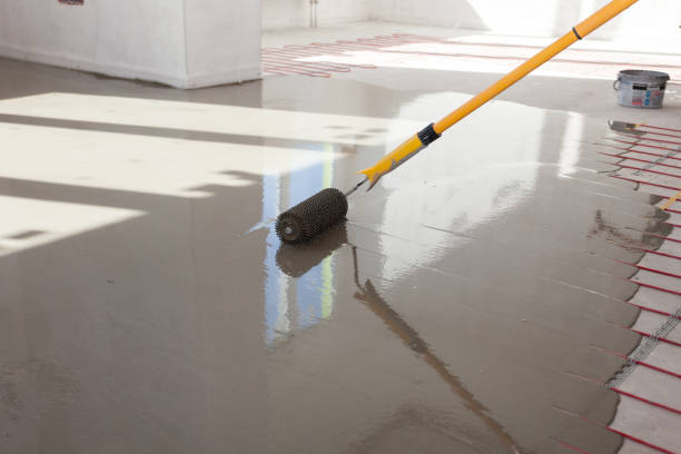 istock Electric floor heating system installation in new house. Worker align cement with roller 800397410