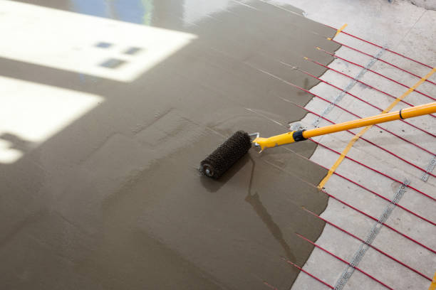 istock Electric floor heating system installation in new house. Worker align cement with roller 800397966