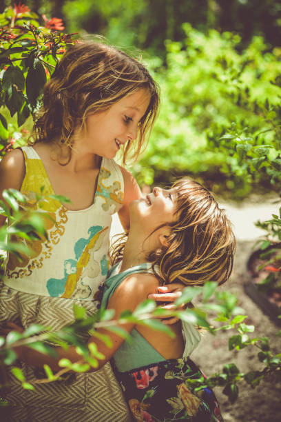 Two little girls in a lush beautiful garden setting. Children interacting in nature