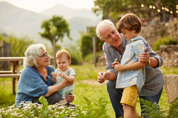 grands-parents, parlant à des enfants en yard - family retirement smiling multi generation family photos et images de collection