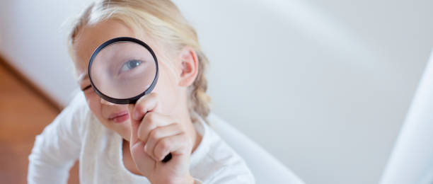 istock Cute little girl looking through a magnifying glass 800423136