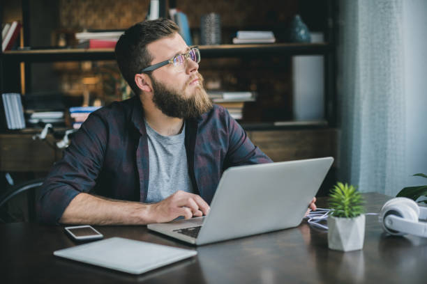 istock pensive bearded man typing on laptop while sitting at home 800423892
