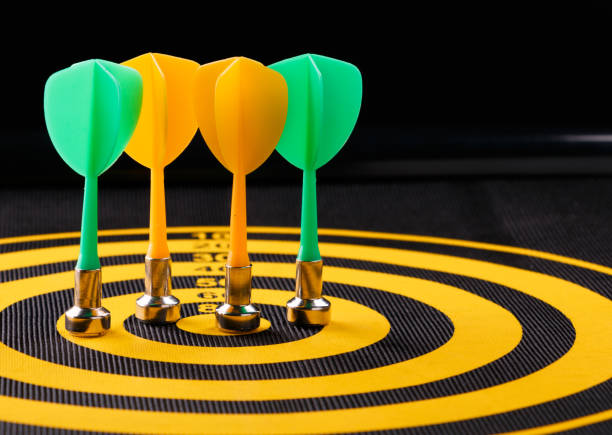 istock Magnetic dart arrows on yellow dart board. black background 800426720