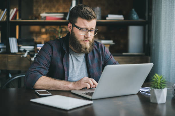 istock young caucasian man working on laptop while sitting at home 800427130
