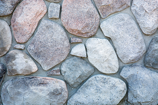 natural river rock mortared together on stone wall closeup background image