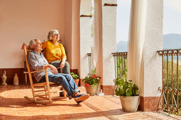 Senior couple sitting on rocking chair at home Senior couple sitting on rocking chair. Man and woman are resting at home on sunny day. They are wearing casuals. rocking chair stock pictures, royalty-free photos & images