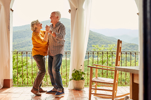 Loving senior couple dancing in balcony at home