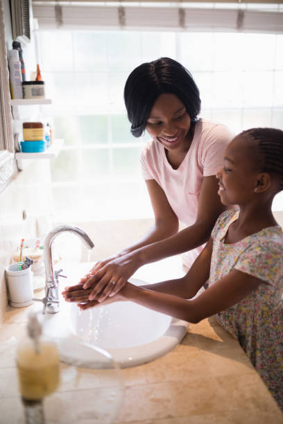 istock Mother looking at daughter while washing hands in bathroom 800445222