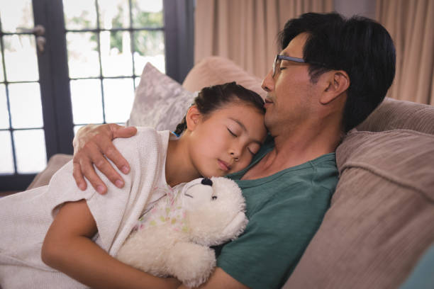 istock Father and daughter relaxing on sofa in living room 800445492