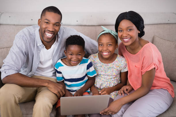 istock Happy family holding laptop while sitting on sofa at home 800447570