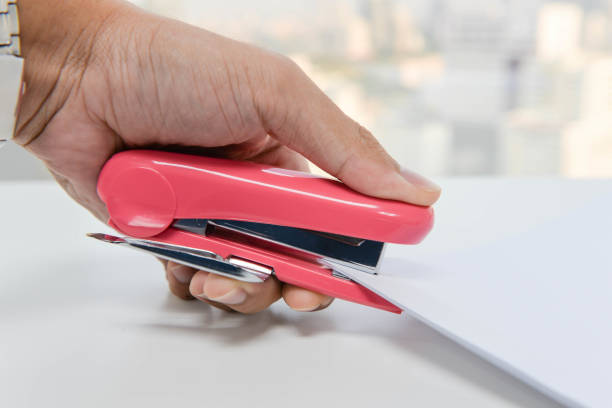 istock Human hand is stapling the paper with pink stapler 800451454