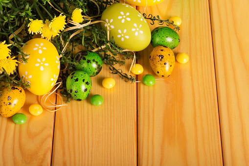 Easter eggs, candy, flowers, herbs on a background of light wood. Close-up.