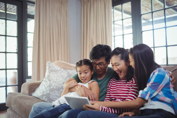 istock Smiling family using digital tablet together in living room 800472124