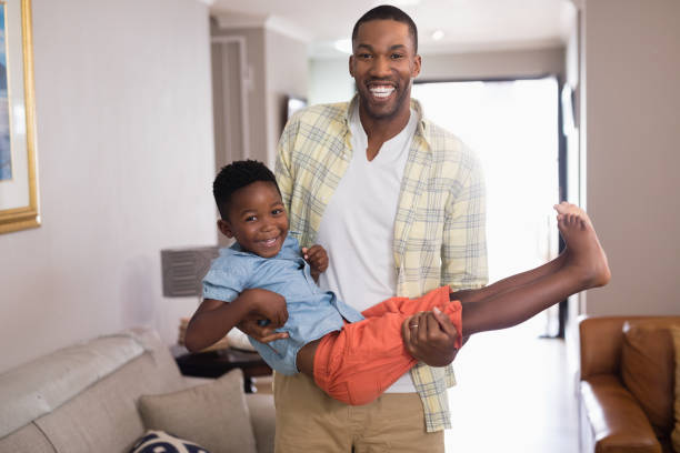 istock Playful father carrying son in living room 800476070