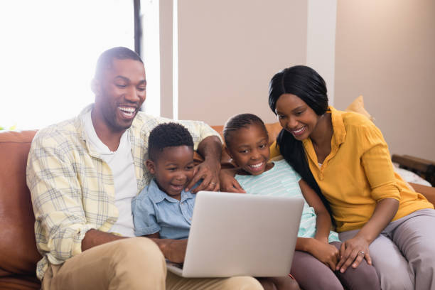 istock Happy parents and children using laptop while sitting on sofa 800476514
