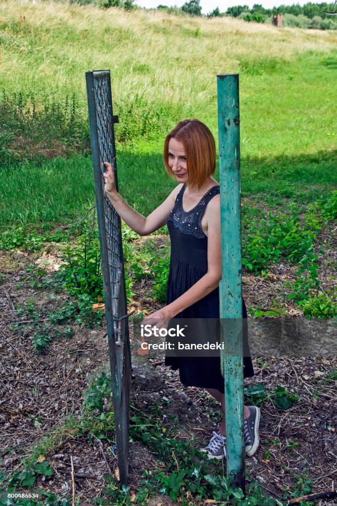 Girl on the iron gate Girl posing behind an old iron gate. Since the fence is only gate remained intact. Anticipation Stock Photo