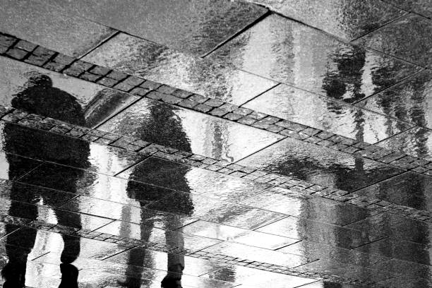 istock Blurry reflections of two person on a rainy sidewalk 800488710