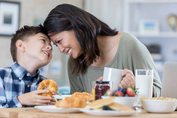 Playful mom enjoys breakfast at home with her son