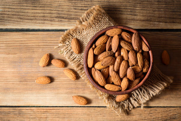 istock Almonds in ceramic bowl on wooden background 800495872
