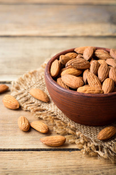istock Almonds in ceramic bowl on wooden background 800495990