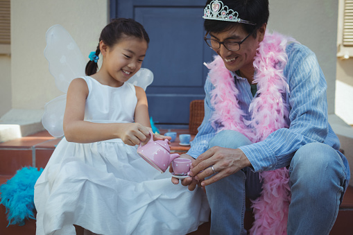Father and daughter in fairy costume having a tea party at home